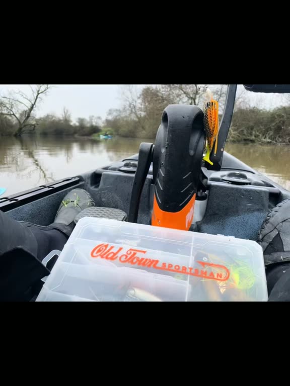 Boîte de leurres posée sur un kayak, au bord de la rivière